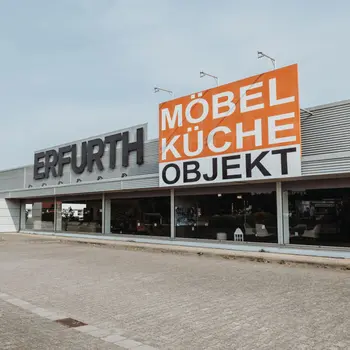 Gebäudefassade mit Schriftzügen ERFURTH und MÖBEL KÜCHE OBJEKT, Schaufenstern und Parkplatz